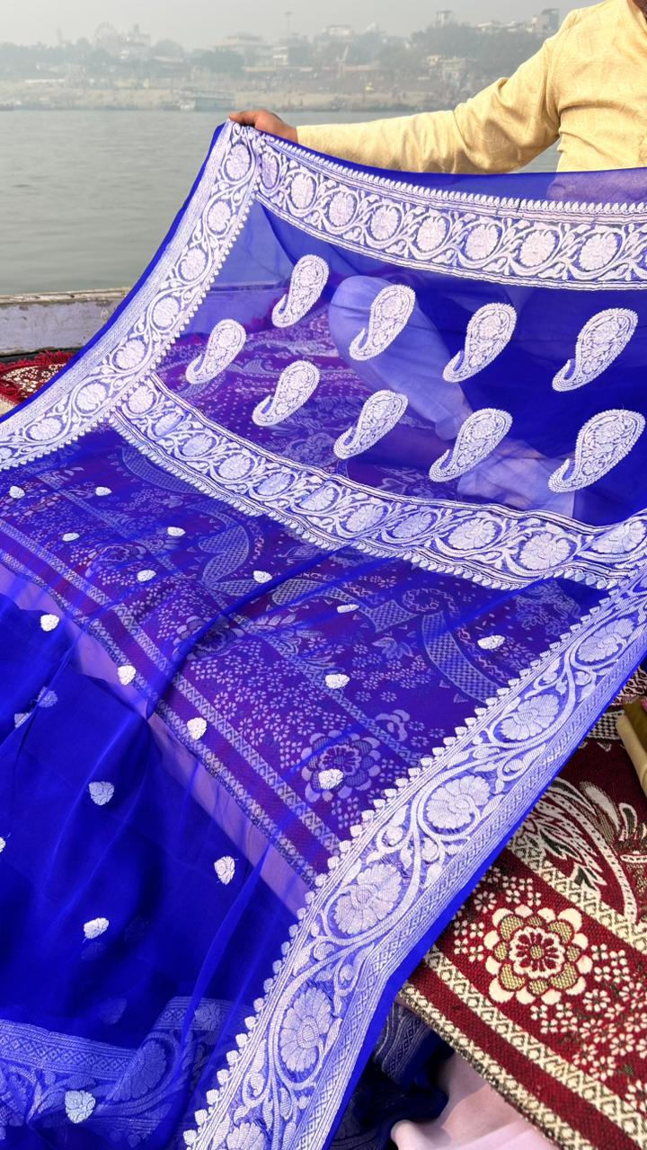 Blue saree with white patterns held by a person on a textured surface